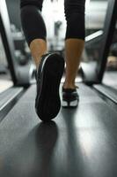 proche en haut de Unique de baskets de méconnaissable athlète le jogging sur une tapis roulant. photo