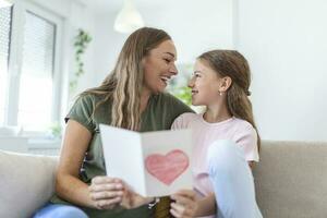 content de la mère journée. enfant fille félicite maman et donne sa carte postale. maman et fille souriant et étreindre. famille vacances et unité. photo