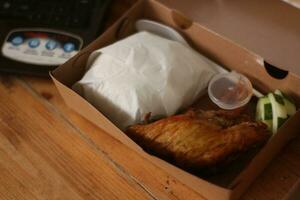 frit poulet dans une boîte sur une en bois tableau. photo