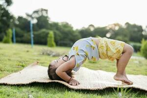 fille Faire gymnastique sur une aptitude tapis solitaire à Accueil Faire yoga Faire pont Naturel retour pliez souple des gamins Faire gymnastique des exercices. sport, apprentissage, aptitude, élongation, actif mode de vie concept. photo