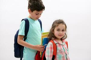 adolescent garçon portion le sien plus jeune sœur à pack sa cartable, isolé plus de blanc studio Contexte photo