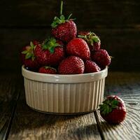 mûr savoureux des fraises dans une céramique bol sur une en bois tableau. photo