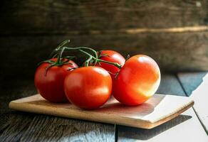 une branche de mûr tomates sur une Coupe planche dans le cuisine. photo