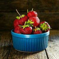 mûr savoureux des fraises dans une céramique bol sur une en bois tableau. photo