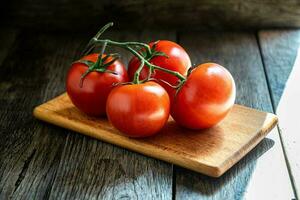 une branche de mûr tomates sur une Coupe planche dans le cuisine. photo