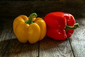 Jaune et rouge cloche poivrons sur une en bois tableau. photo