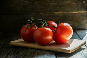 une branche de mûr tomates sur une Coupe planche dans le cuisine. photo