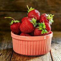 mûr savoureux des fraises dans une céramique bol sur une en bois tableau. photo