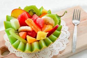 salade de fruits frais avec kiwi, banane, pêche, orange, orange rouge, abricot et melon dans un bol d'ananas fait à la main. photo