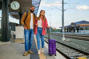 content couple est permanent à chemin de fer station et attendre pour arrivée de leur train. photo