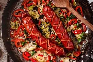 saucisse et mélange de légumes frais frits dans la poêle rustique, piments forts frais, tomates et herbes.