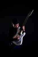 Jeune homme en blouson de cuir noir avec guitare électrique en studio photo