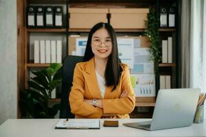 femme asiatique confiante avec un sourire debout tenant un bloc-notes et une tablette au bureau. photo