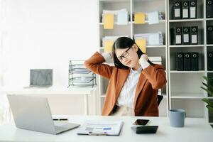 surmené Jeune asiatique femme d'affaires Bureau ouvrier Souffrance de cou douleur après avait une longue journée à sa Bureau bureau. photo