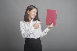 belle femme enseignante tenant un livre sur fond gris photo