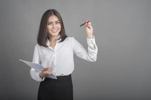 belle femme d'affaires écrit quelque chose sur fond gris photo