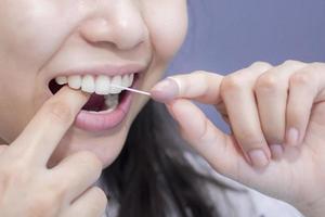 les femmes souriantes utilisent du fil dentaire des dents saines blanches