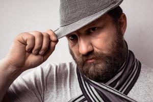 Jeune homme barbu hipster portant un chapeau et une écharpe gris photo