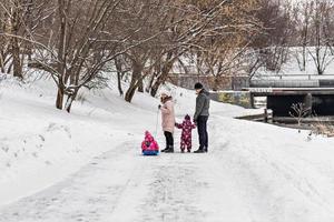une famille avec deux enfants dans un traîneau lors d'une promenade dans le parc