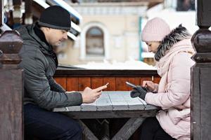 un couple attend sa commande pour déjeuner dans un café de la rue, envoyant des SMS par téléphone. communication avec les gens sur un smartphone. photo