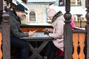 un couple attend sa commande pour déjeuner dans un café de la rue, envoyant des SMS par téléphone. communication avec les gens sur un smartphone. photo
