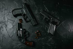 trois armes à feu et balles sur tableau noir.