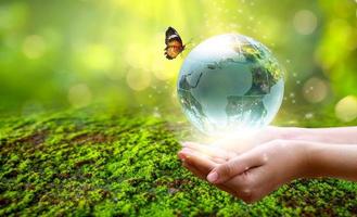 un homme avec un globe de verre concept day terre sauver le monde sauver l'environnement le monde est dans l'herbe de l'arrière-plan flou vert photo