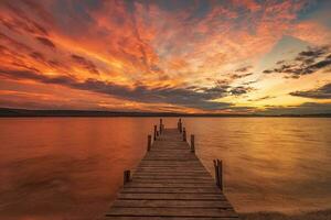 passionnant coloré le coucher du soleil vue de le rive avec une en bois jetée photo