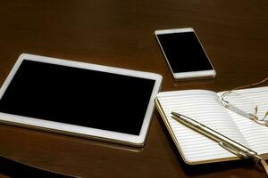Bureau tableau, tablette, lunettes, carnet et stylo. gadgets sur une en bois tableau. photo