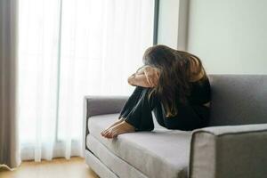 triste femme en pensant à propos problèmes séance sur une canapé dérangé fille sentiment solitaire et triste de mal relation ou déprimé femme désordre mental santé. photo