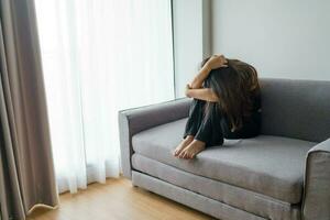 triste femme en pensant à propos problèmes séance sur une canapé dérangé fille sentiment solitaire et triste de mal relation ou déprimé femme désordre mental santé. photo