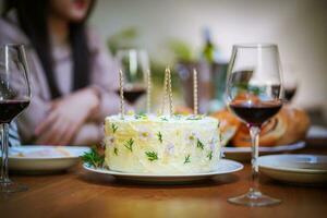 de bonne humeur copains profiter Accueil anniversaire vacances faire la fête. asiatique sœur applaudissement en buvant rouge du vin célébrer avec anniversaire gâteau photo