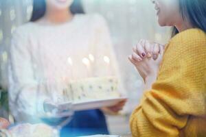 de bonne humeur copains profiter Accueil anniversaire vacances faire la fête. asiatique sœur applaudissement en buvant rouge du vin célébrer avec anniversaire gâteau. photo