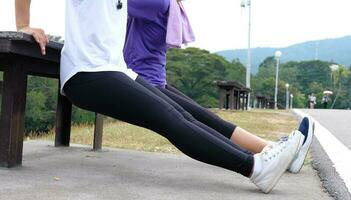 Jeune sportif femme faire des exercices avant aptitude formation chauffage en haut dans en plein air. photo