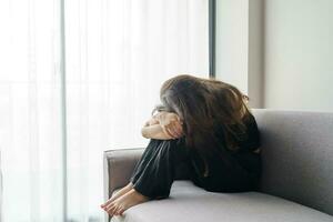 triste femme en pensant à propos problèmes séance sur une canapé dérangé fille sentiment solitaire et triste de mal relation ou déprimé femme désordre mental santé. photo