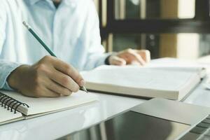 étudiant en train de préparer pour Université test, examen, en train de lire livre, en train d'étudier cahier de texte, l'écriture Remarques, fabrication sommaire pour classe rapport. photo