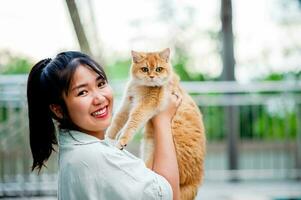 femme en portant chat en jouant à Accueil avec l'amour pour chats le sourire des reflets dans le sien liaison avec le sien duveteux animal de compagnie chat. le relation de gens et chats, chat les propriétaires, national chats, graisse chats photo