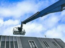 grue élévatrice avec plate-forme de levage sur le toit d'un bâtiment photo