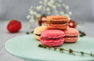 macarons colorés français. macarons pastel colorés sur fond clair avec des fraises fraîches. concept de flou artistique. photo