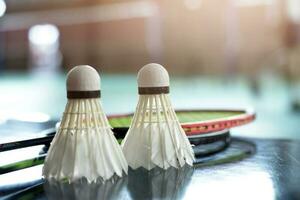 volant de badminton blanc crème et raquette au sol dans un terrain de badminton intérieur, espace de copie, mise au point douce et sélective sur les volants. photo