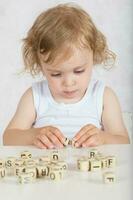 petit fille compose mots de des lettres. fermer photo