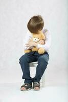 six ans vieux garçon séance sur le chaise avec peluche nounours ours. photo