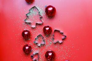 catégoriquement biscuit coupeurs sur une rouge Contexte. paillettes et Noël jouets sur une rouge Contexte photo