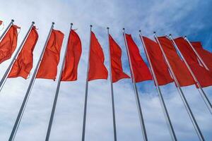 une lot beaucoup rouge drapeaux. rouge drapeaux dans le bleu ciel avec blanc des nuages. photo