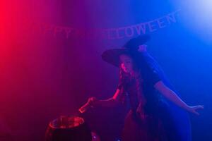 enfant fille sorcière en train de préparer une potion dans le chaudron à Halloween vacances. photo