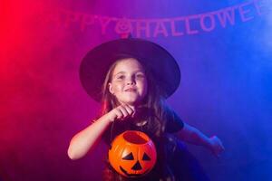 marrant enfant fille dans sorcière costume pour Halloween avec citrouille jack. photo