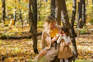 mère réconfortant sa pleurs peu fille dans l'automne la nature. émotions et famille concept. photo