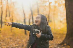 enfant fille en utilisant un démodé caméra dans l'automne la nature. photographe, tomber saison et loisir concept. photo
