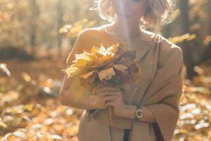 femme en portant bouquet de l'automne érable feuilles. saison et tomber concept. photo