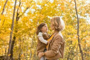 Jeune mère avec sa triste en colère peu fille dans un l'automne parc. tomber saison, parentalité et les enfants concept. photo